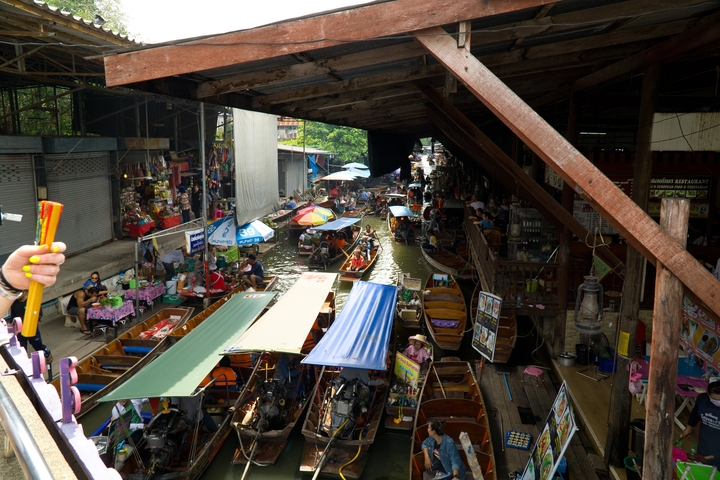 Busy floating market scene with people and boats.