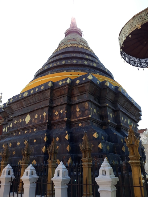 A golden stupa with intricate design details against a clear sky.