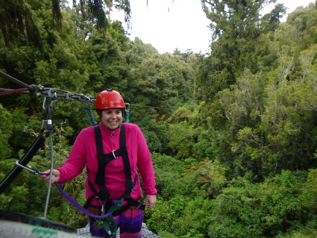 A person on a zip line above a forest.
