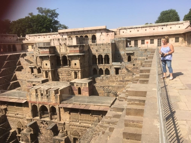       Tourist exploring an ancient stepwell with intricate stone carvings.
  