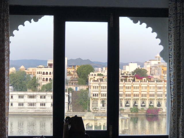       View through a window of the cityscape and distant mountains.
  