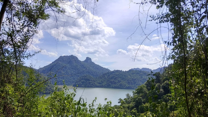 Lake view with lush green mountains under a clear sky in Vietnam.