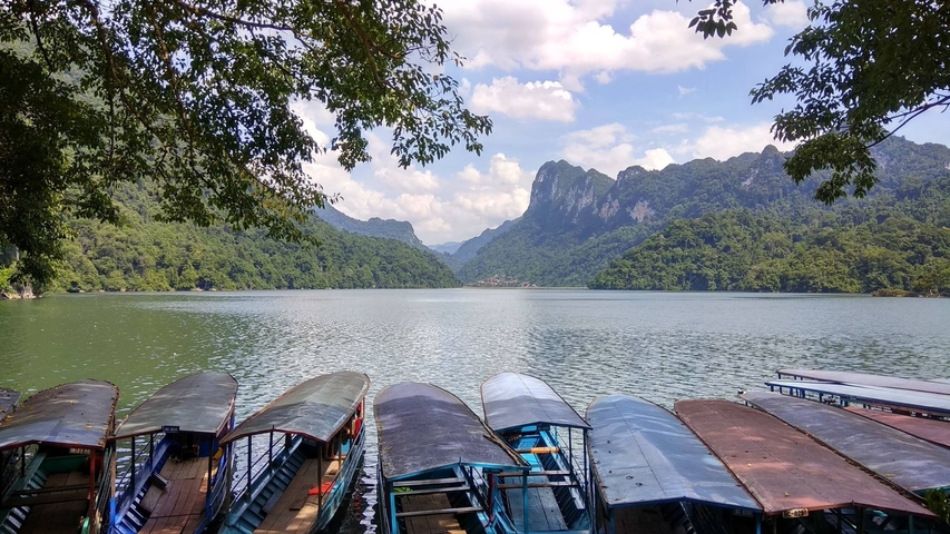 Scenic view of a lake surrounded by mountains and trees in Vietnam.