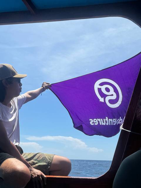       A person holding a purple flag on a boat.
  