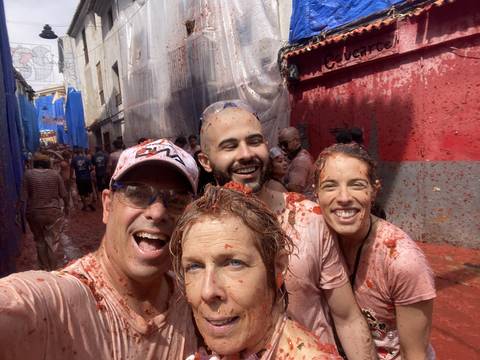       Group selfie during a tomato fight event, all participants are covered in tomatoes.
  