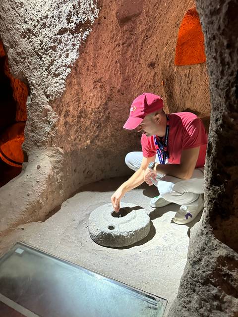       Person in a cave showcasing an ancient tool.
  