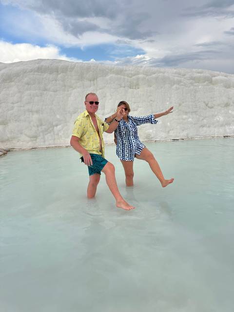       Two people posing in water against a backdrop of white formations.
  
