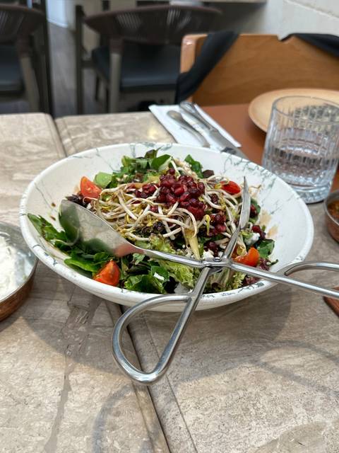       Salad with pomegranate seeds and greens on a table.
  