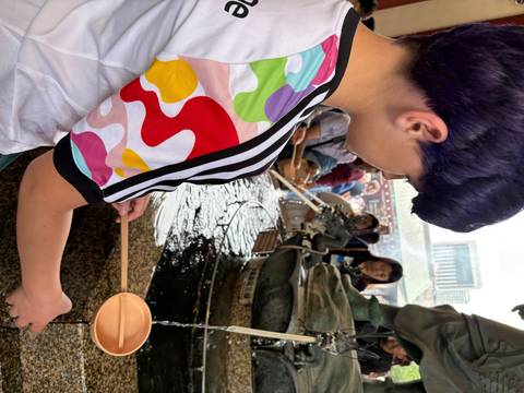       Person washing hands at a temple water fountain.
  