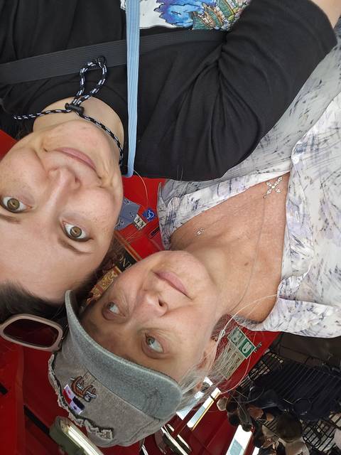       Two people posing on a bus, looking at the camera.
  