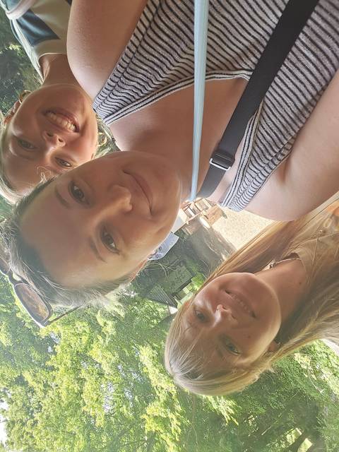       Three people posing outdoors in a wooded area.
  