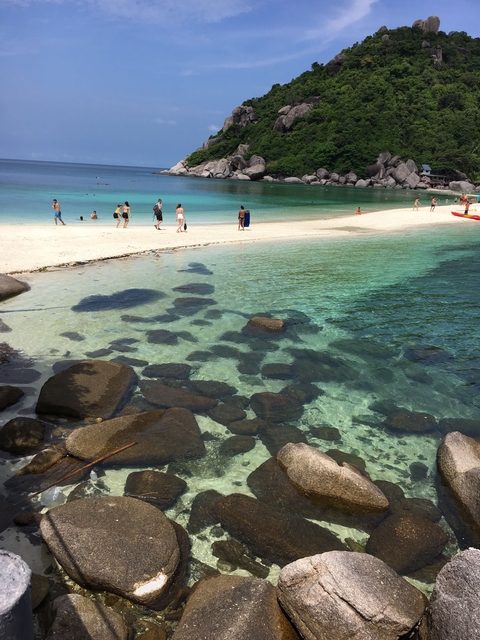       People walking on a sandbar in clear water.
  