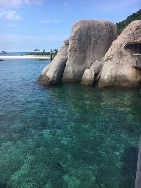       Clear water with rock formations and a small dock.
  