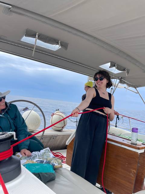       Person handling ropes on a yacht while sailing.
  