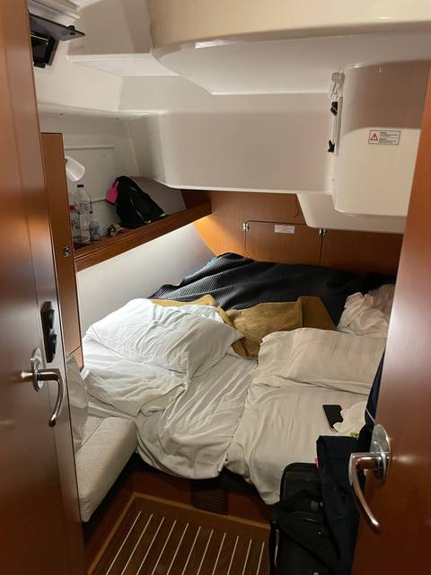       Bed in a yacht cabin with disheveled sheets.
  