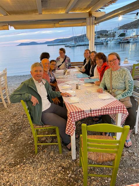      Group of people dining outdoors at a waterfront restaurant.
  