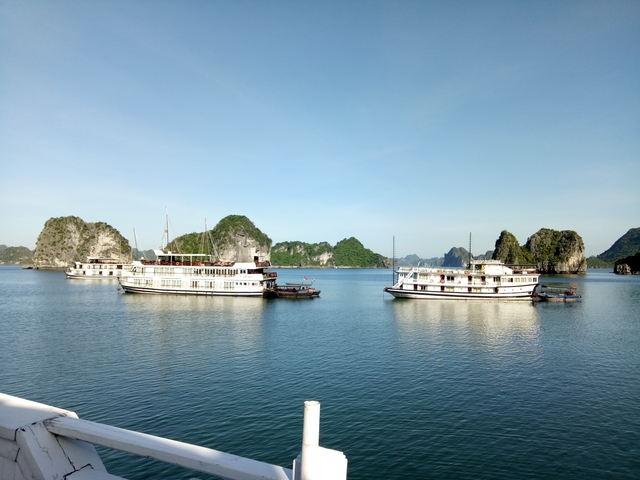 Boats on a serene bay with limestone mountains in the background.