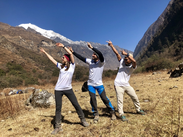       Three people posing with hills and snow-capped mountains in the background.
  