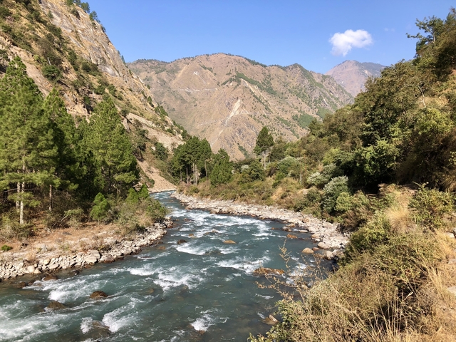       A river flowing through a lush green valley with mountains.
  