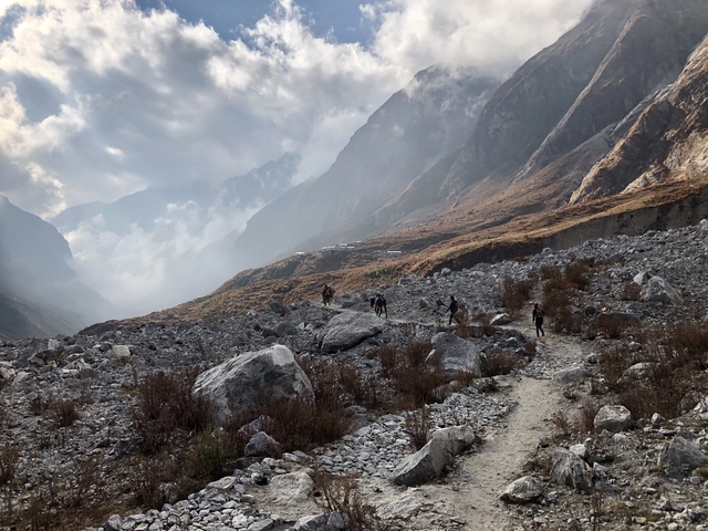      Hikers walking through a rocky mountain landscape with mist.
  