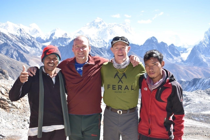Four men posing with snowy mountains in the background.