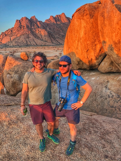 Two people posing on rocks during sunset.