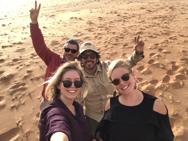 Group selfie in a sandy desert landscape.