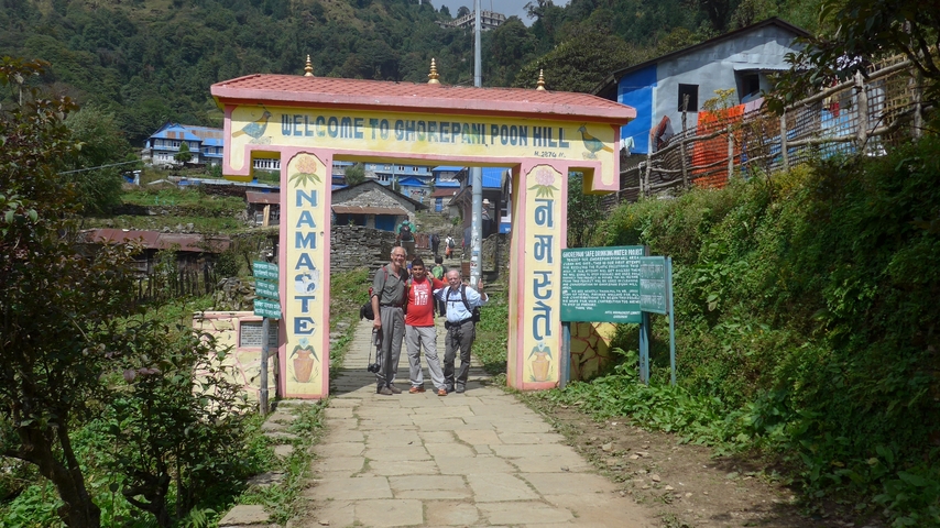 People standing at the entrance to a hill station with signs.