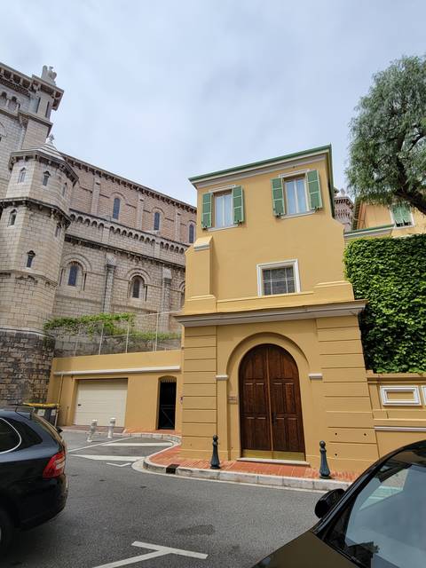       Street view of a yellow building with green shutters.
  