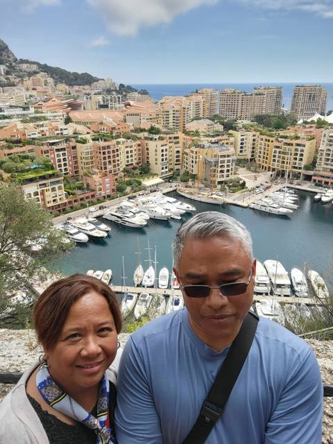       Couple posing with harbor view and yachts.
  