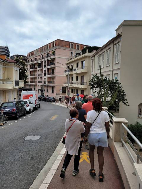       People walking up a street with pink buildings.
  