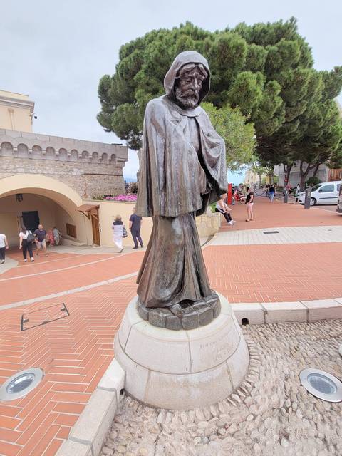       Statue of a man in a cloak in a public square.
  