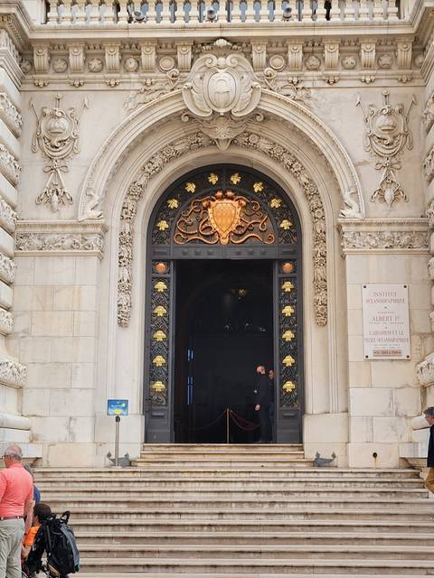       Ornate building with decorative archway and people.
  