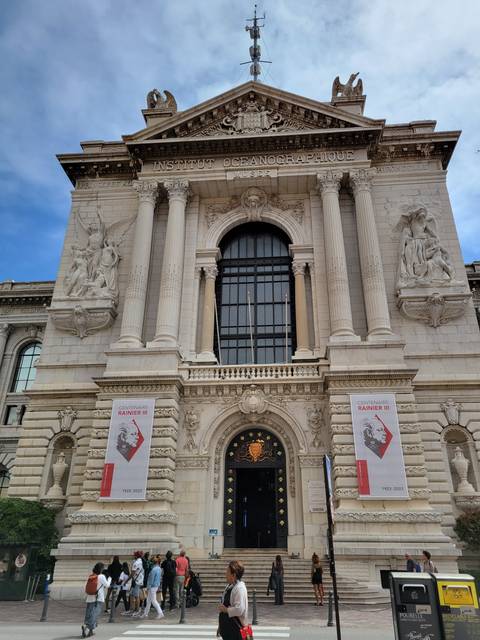       Elegant building with columns and banners and people around.
  