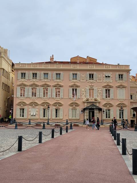       Beige building with decorative facade and people walking.
  