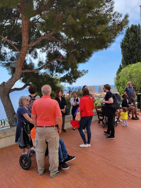       Tour group in a park with city view behind.
  