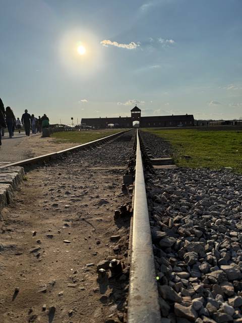       Railway tracks leading to a historical site at sunset.
  