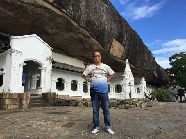 Person standing outside a rock-temple complex under a clear sky.