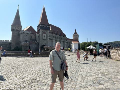       A group of people in front of a picturesque castle.
  