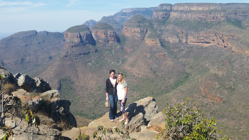 Two people standing at a viewpoint overlooking the Blyde River Canyon.