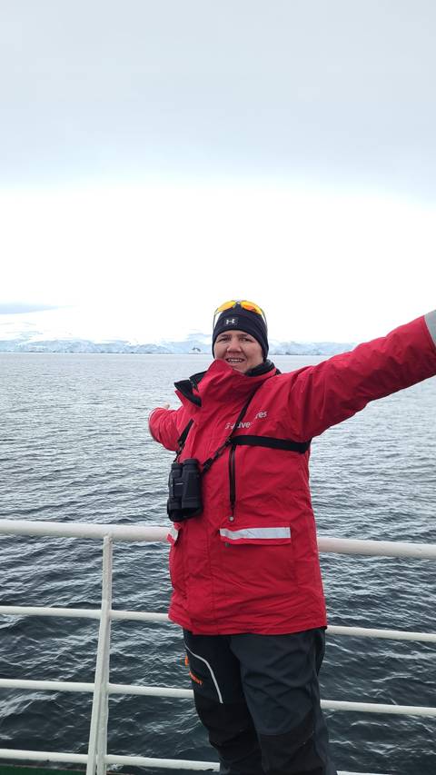 Person in cold-weather gear standing on a ship.