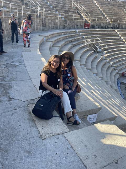 Two women sitting on stairs of an ancient amphitheater.