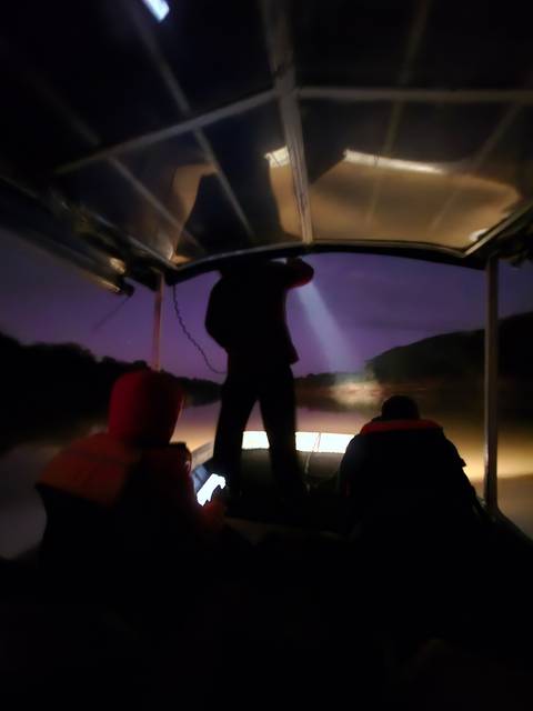       Blurry image of a person on a boat during nighttime.
  