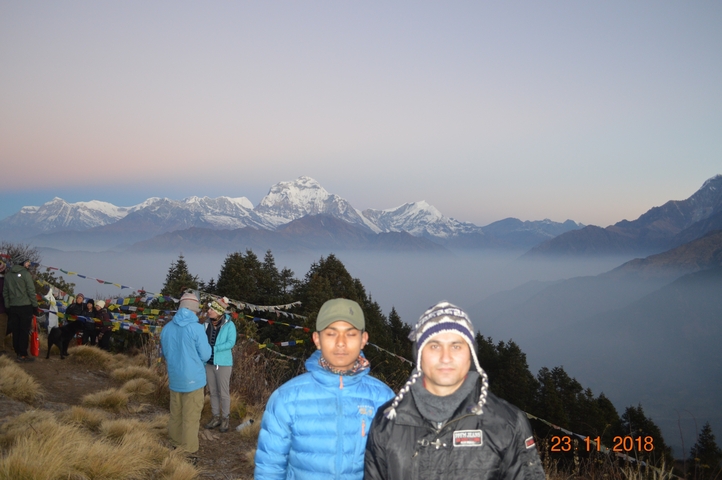       Group of people with prayer flags and mountains in the background.
  