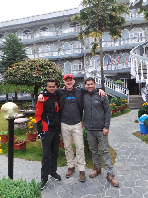       Three people posing at a courtyard with a building in the background.
  
