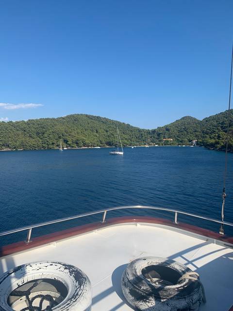 A boat in a serene bay with forested hills.