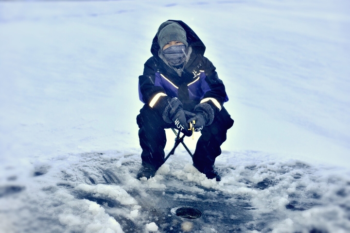       Person ice fishing in winter gear.
  