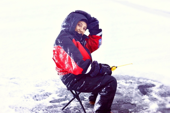       Person ice fishing while sitting on a chair.
  