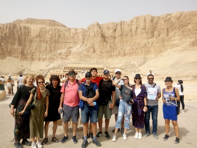A group of people posing in front of the Mortuary Temple of Hatshepsut.