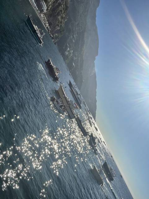       Boats on a sunlit sea with hills in the background.
  